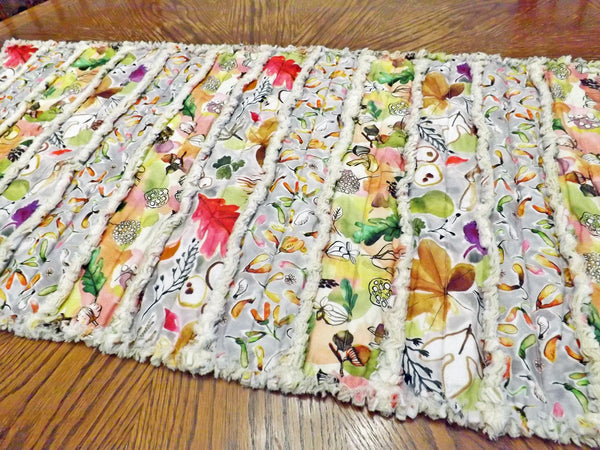 Acorns and autumn leaves rag quilt table runner with bright autumn colors on wood table